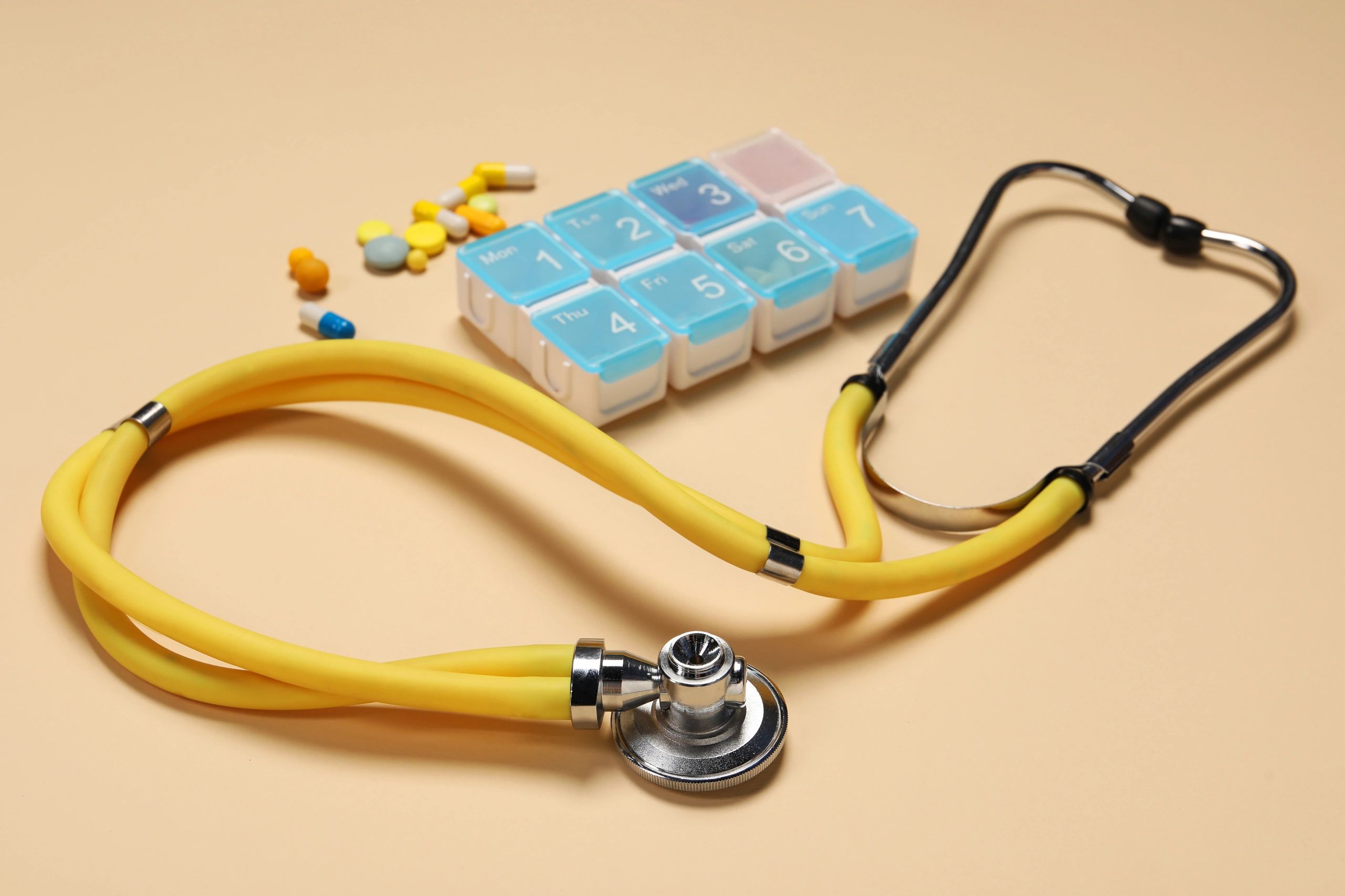 Stethoscope and pills on a neutral background
